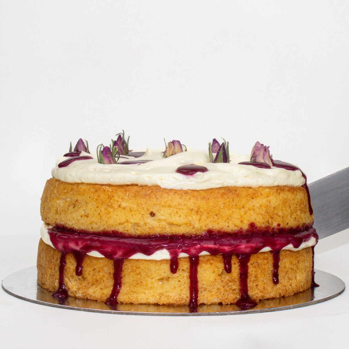 image of the raspberry, rhubarb and cream cake being cut by a large silver knife