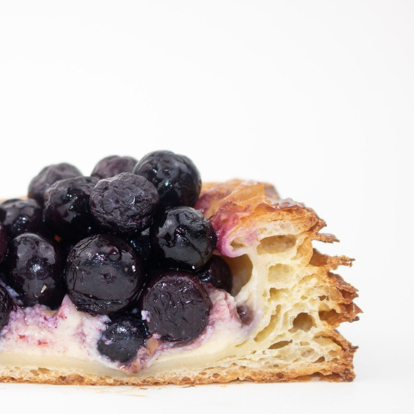close up image of blueberry danish. shows blueberries, custard and inside of pastry 