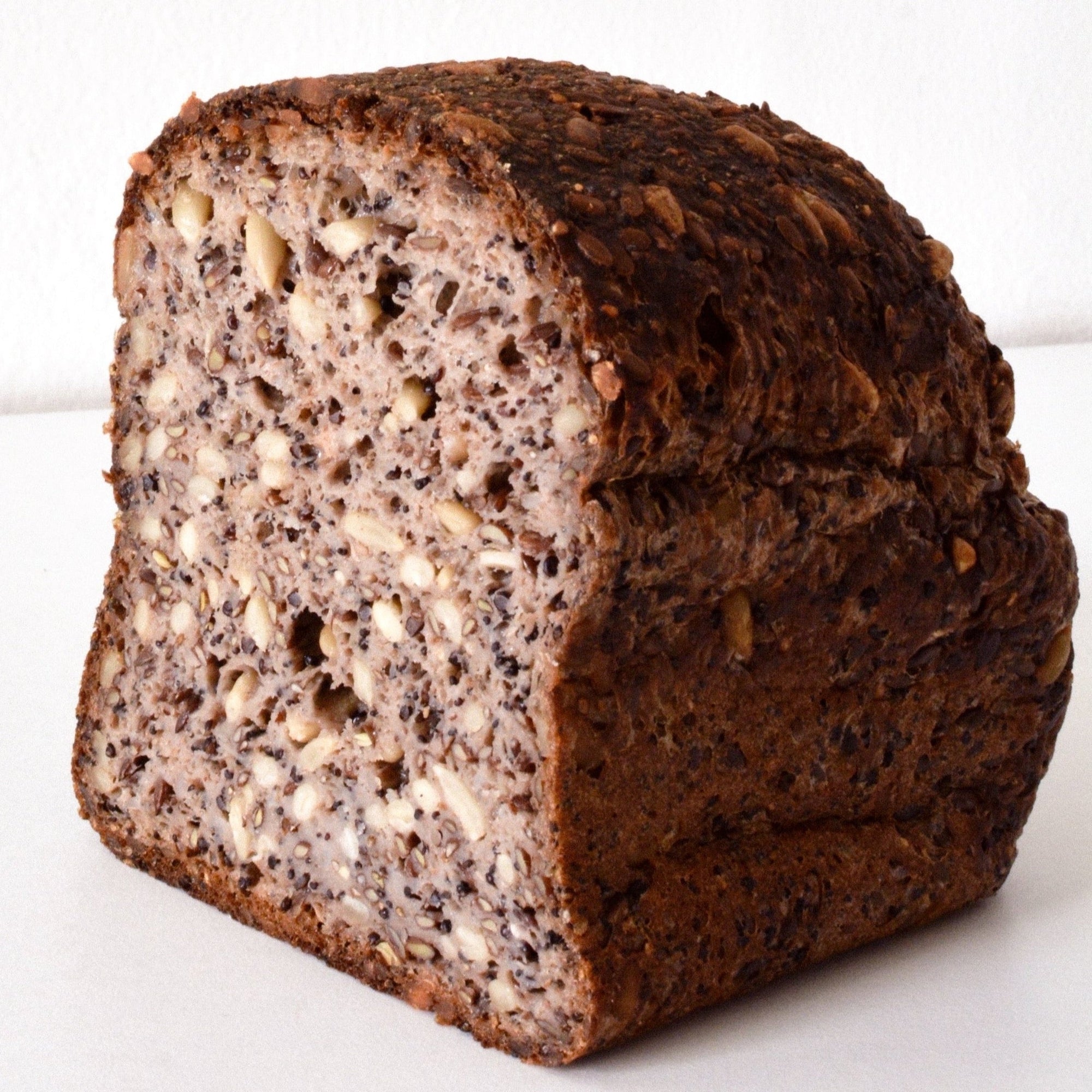 image of the inside of the sprouted quinoa loaf, it is a lighter brown and contains a multitude of seeds and grains 