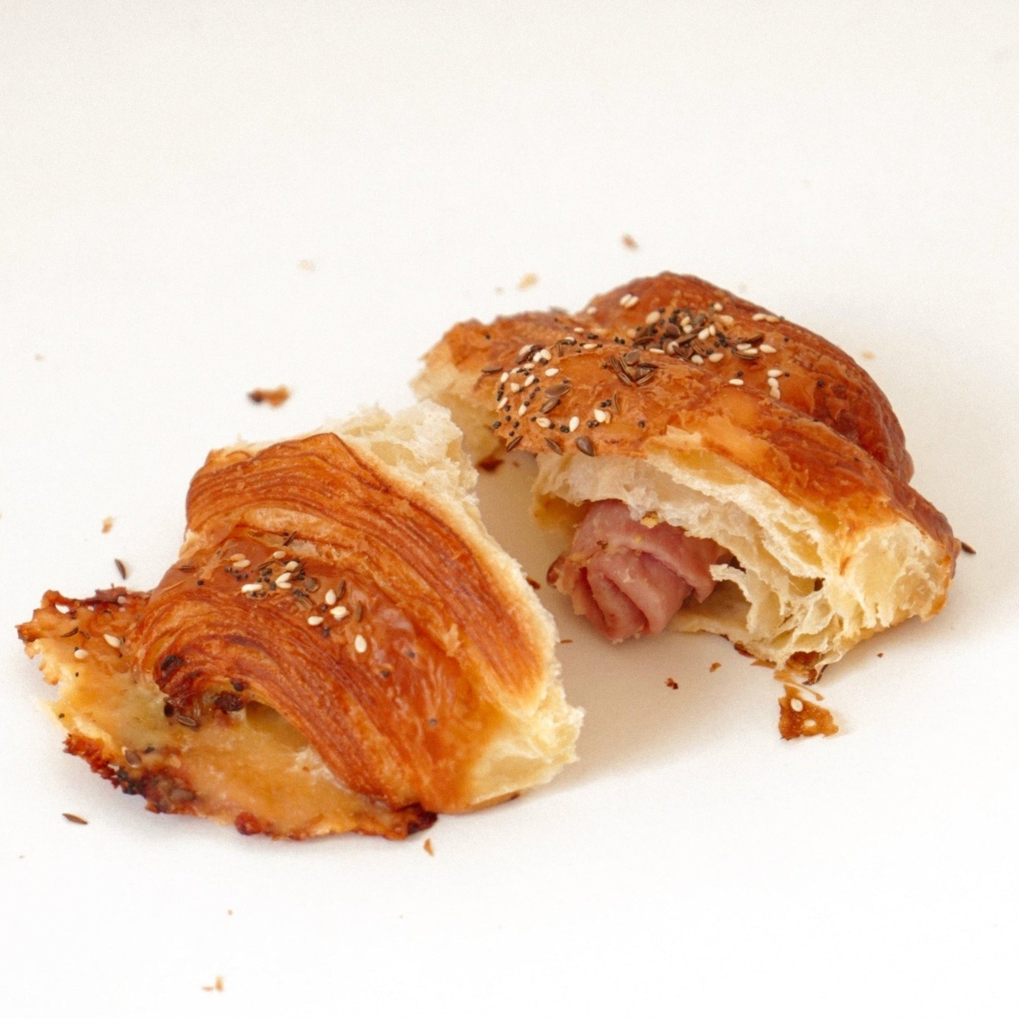 image of ham and cheese croissant that has been ripped in half 