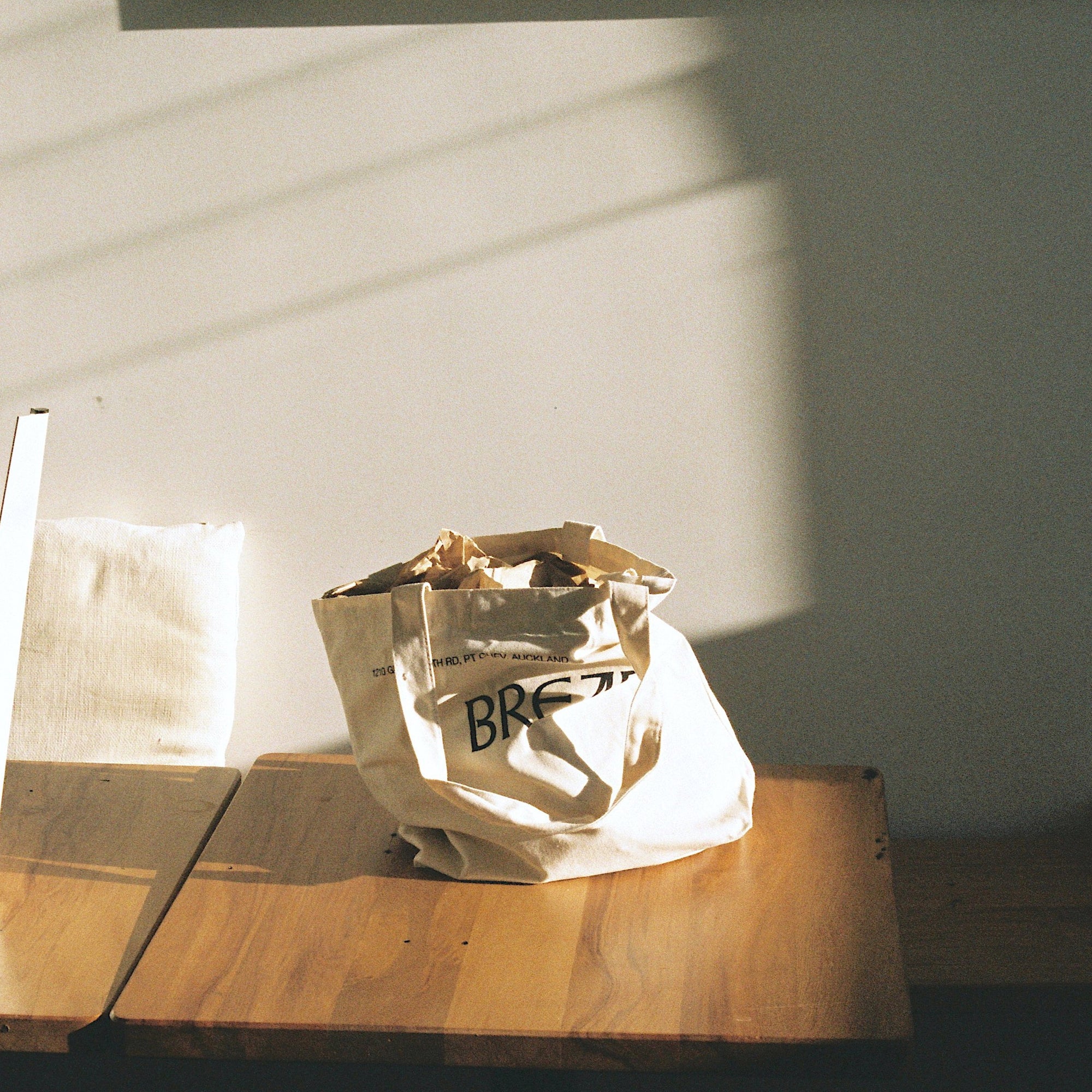 image of a daily bread branded tote bag on a wooden table in the sunlight