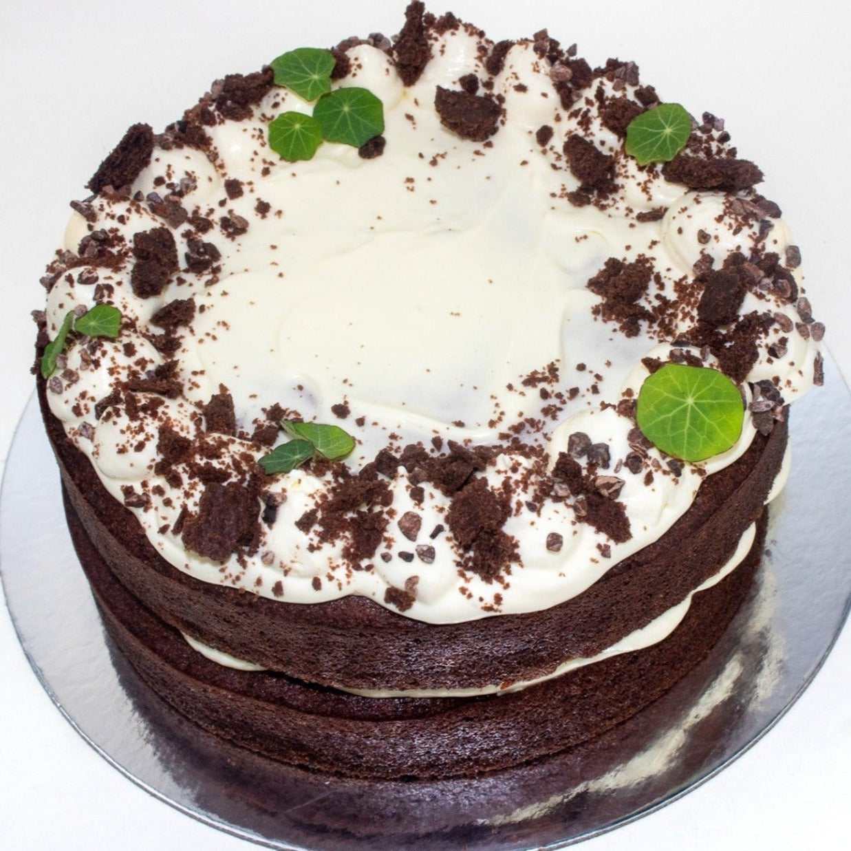 image of the top of the cake showing the white icing, green leaf and cookie pieces for decoration