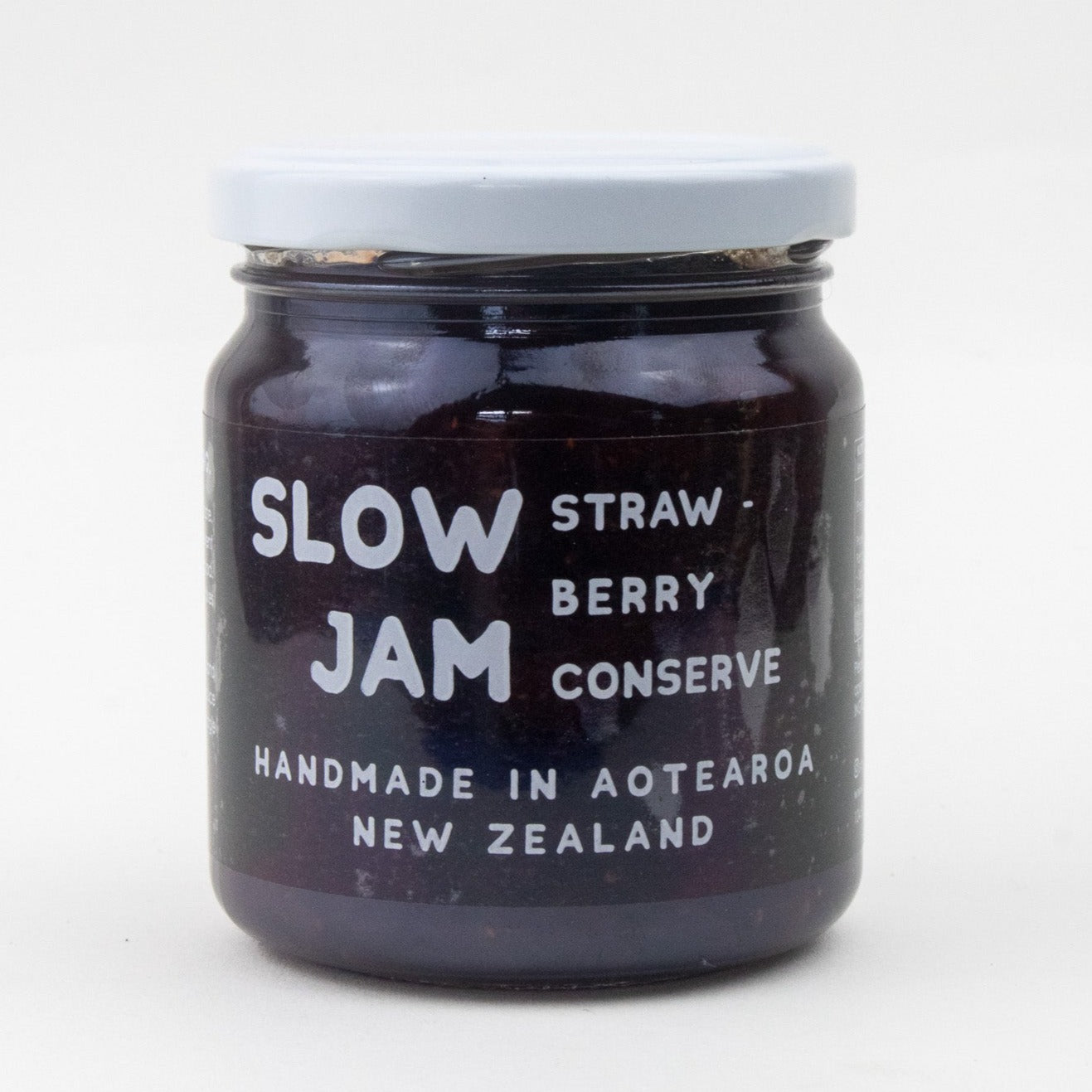 Image of a clear jar with white lid and writing. the text states that the jar is full of handmade dark strawberry conserve 