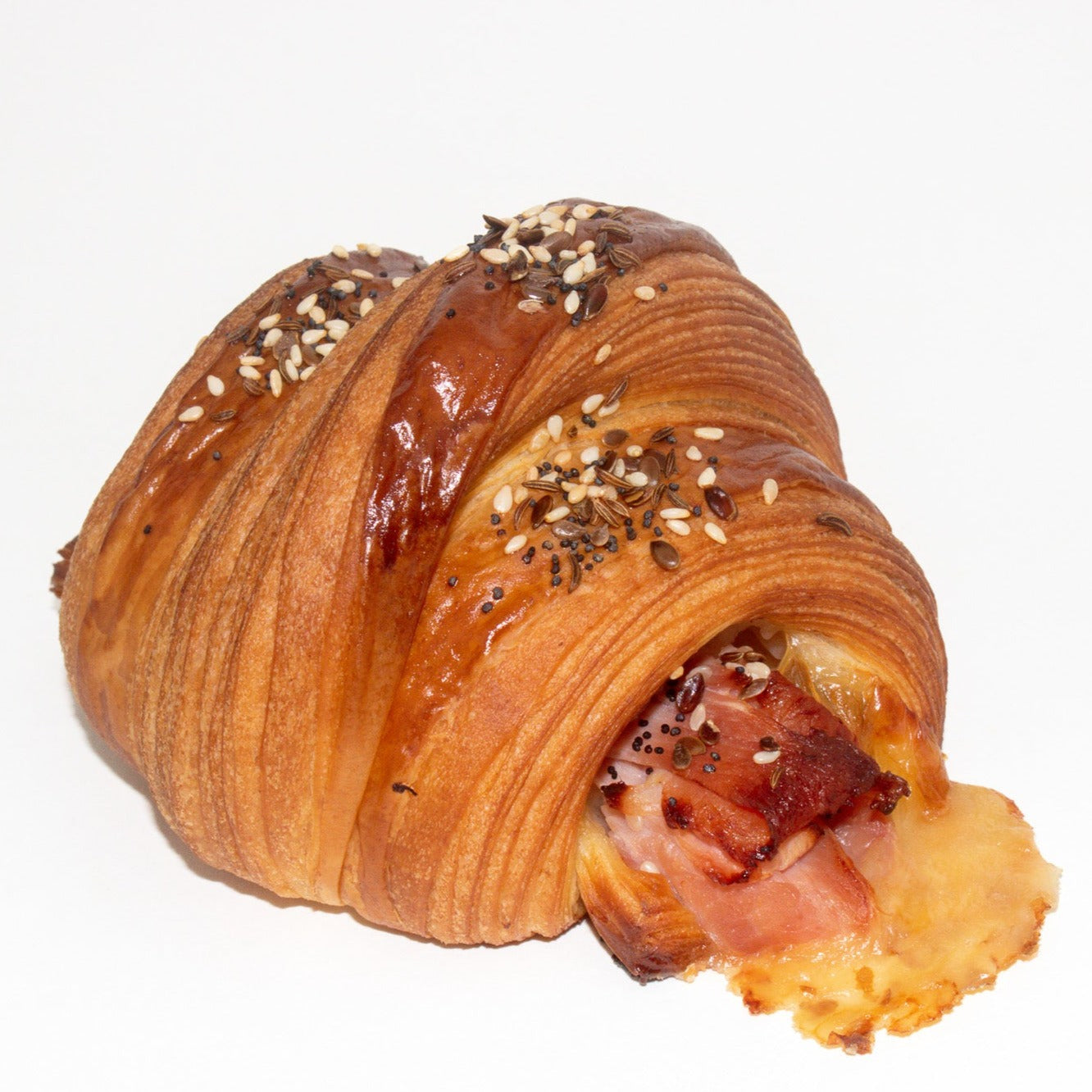 Image of croissant with ham and cheese in the middle, and seeds on the top