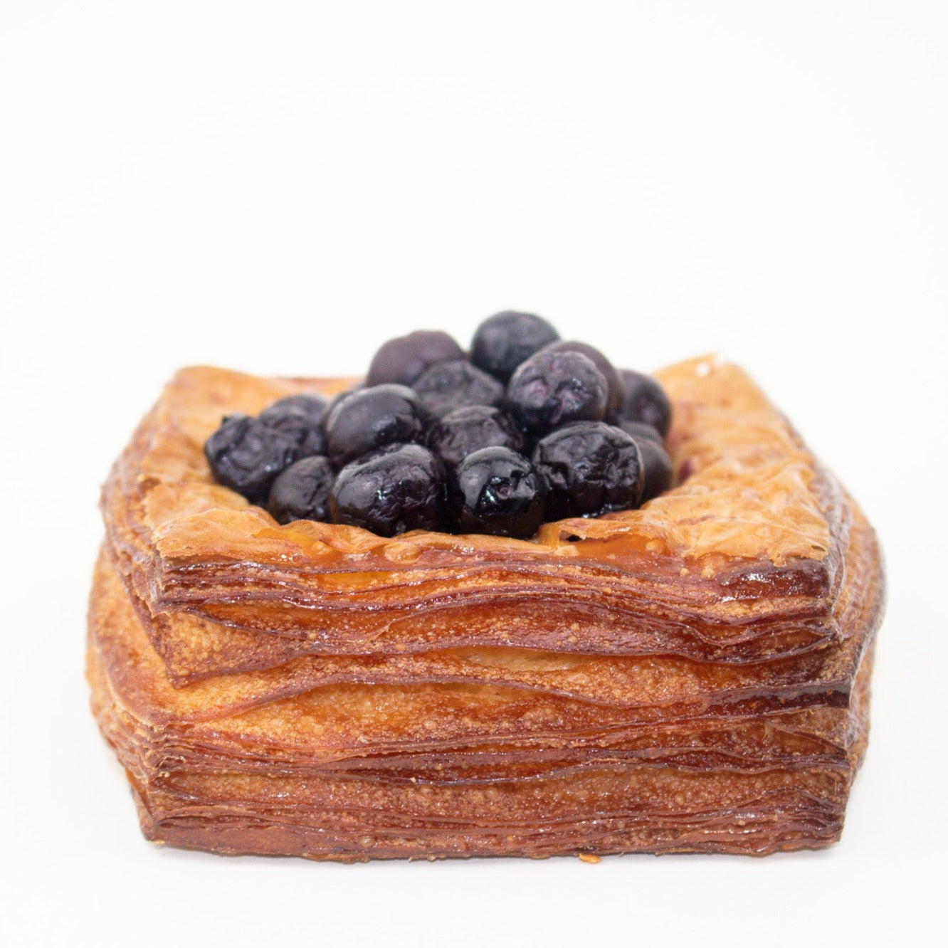 image of the a blueberry danish. many blueberries sit on top of a layered pastry