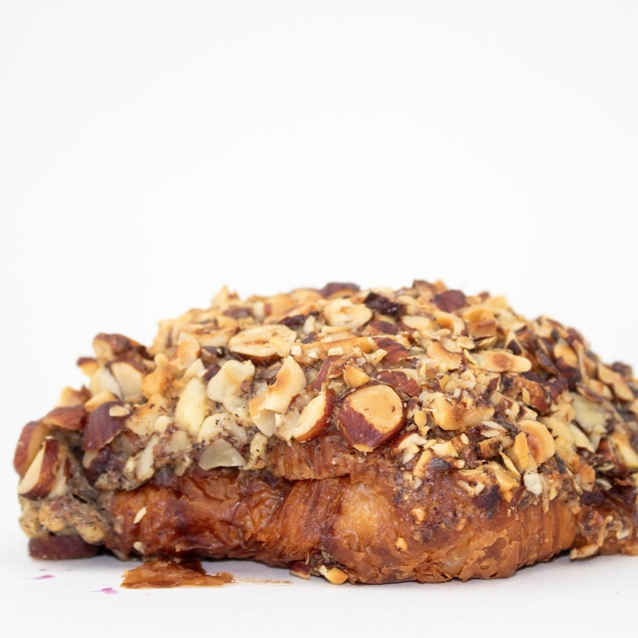 close up image of a croissant covered in hazelnut pieces 