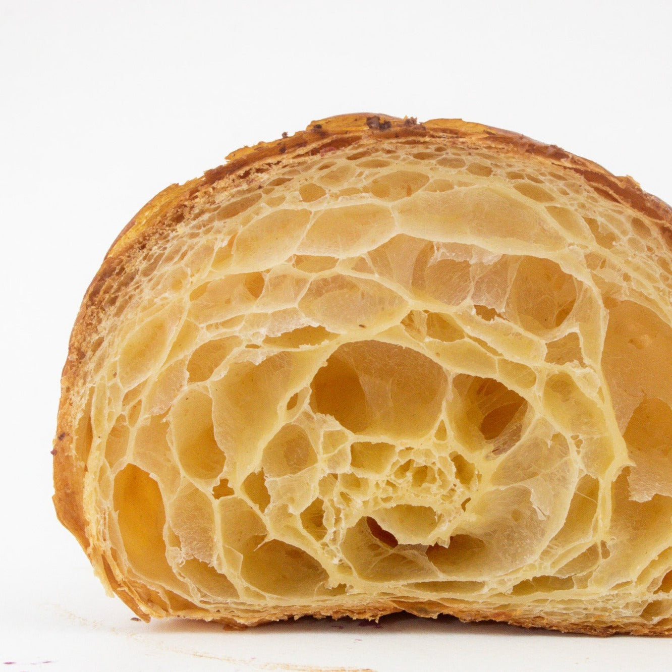 image of the inside of a croissant that has been cut in half to show the layers & lamination