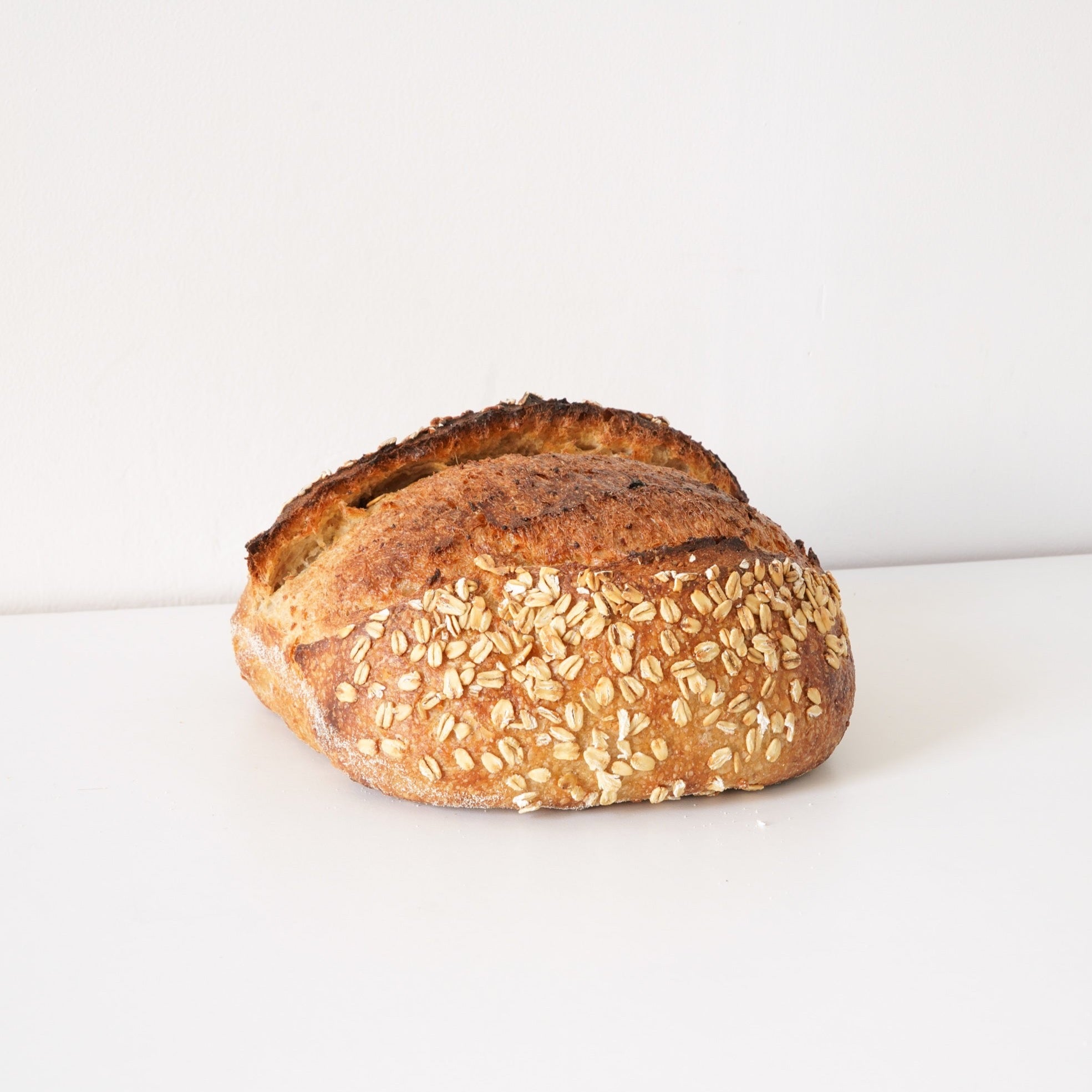 image of the whole sourdough loaf with oat pieces on top. 
