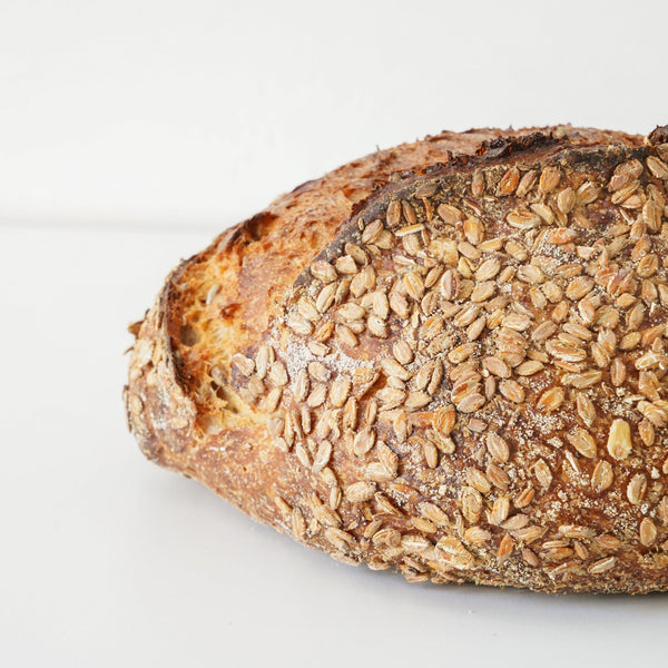 close up image of a golden brown loaf that is covered in smoked bye berries 