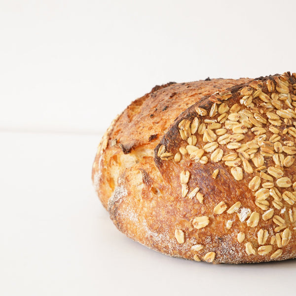 image of half a sourdough loaf with oat pieces on top