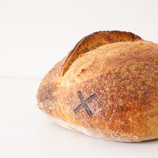 Close up image of a golden brown load of domed sourdough