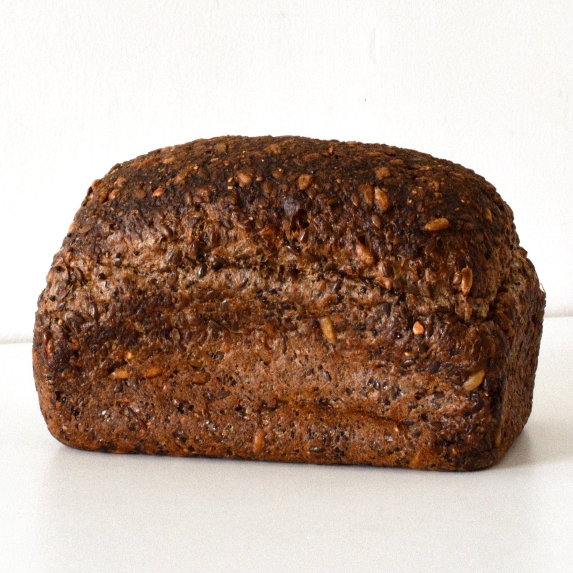 full image of the sprouted quinoa loaf, it is a dark brown and contains a multitude of seeds and grains 